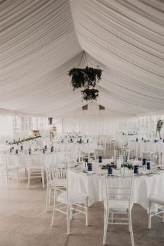 tables and chairs are set up in a tent with white draping on the ceiling