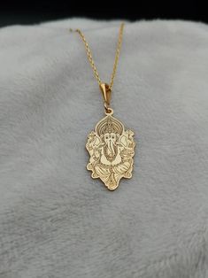 Celebrate spirituality and elegance with this exquisite Ganesha Necklace, crafted in 14K gold. This handmade piece features a delicate depiction of Lord Ganesh, making it a perfect religious charm necklace for those who cherish spiritual symbols. Its tiny and intricate design adds a subtle yet meaningful touch to any outfit, ideal for daily wear or special occasions. ⚜️ Package included: One Handmade Necklace ⚜️ Pendant Sizes: 14 / 16 / 18 / 20 / 22 / 24 / 26 / 28 / 30 mm ⚜️ Necklace Length: 14 Gold Plated Necklaces For Diwali Gift, 22k Gold Jewelry For Navratri Gift, Spiritual Gold Plated Necklaces With Intricate Design, Spiritual Gold-plated Necklaces With Intricate Design, Spiritual Gold Plated Necklace With Intricate Design, Gold Plated Temple Necklace As Festive Gift, Festive Gold-plated Temple Necklace As A Gift, 22k Gold Temple Necklace With Intricate Design As Gift, Yellow Gold Jewelry For Puja Diwali