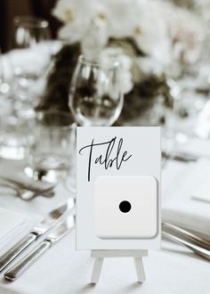 there is a place card on top of a table with silverware and flowers in the background