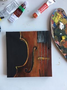 an art project with paint, acrylic paints and a violin on the table