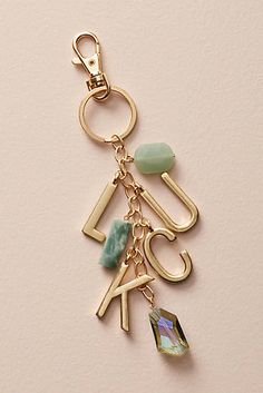 a gold keychain with charms hanging from it's sides on a pink surface