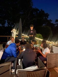 a group of people sitting on top of a wooden deck next to each other at night