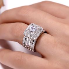 a woman's hand with a diamond ring on top of her finger and an engagement band