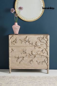 a white dresser sitting next to a blue wall with a mirror on top of it