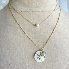 Legend has it that finding a sand dollar during a beach stroll is considered a lucky omen. So take a little bit of the beach and good luck with you wherever you go with our gorgeous Sand Dollar Charm Necklace. Features our most loved satellite chain, freshwater pearl, and blue zircon accents. Freshwater Baroque Pearl size: 6 to 8mm Blue Zircon roundel gemstone 4mm 14kt gold fill or sterling silver round beads 2mm 14kt gold fill or sterling silver satellite chain Real sand dollars are preserved a Sand Dollars, Charm Necklace Silver, Gold Charm Necklace, Pearl Choker Necklace, Sand Dollar, Blue Zircon, Pearl Choker, Pearl Size, Baroque Pearls