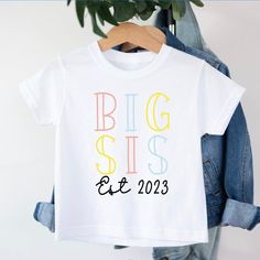 Big Sis t-shirt T-shirt is 100% cotton.  We design & print our products with care & love! We use the best quality vinyls, inks & transfers on all products. * * * * * * * * * * * * * * * * * * * * * * * * * * * * * CARE INSTRUCTIONS: Wash inside out on gentle wash, Do not tumble dry. * * * * * * * * * * * * * * * * * * * * * * * * * * * * * SHIPPING: We want to get your product to you as quickly as possible, your purchase will be shipped through Australia post, Express post is available for selection. * * * * * * * * * * * * * * * * * * * * * * * * * * * * * GUARANTEE: We stand behind our products with a 100% guarantee; if you are unsatisfied with our product, please let us know & we will rectify any issues. We are unable to refund products due to change of mind or those that are personalis Family Matching Custom Print T-shirt For Gender Reveal, White Short Sleeve T-shirt For Gender Reveal, White T-shirt With Name Print For Gender Reveal, White Short Sleeve Shirt For Gender Reveal, White Short Sleeve Tops For Gender Reveal, Gender Reveal T-shirt With Name Print, Short Sleeve T-shirt With Name Print For Gender Reveal, White Letter Print T-shirt For Gender Reveal, White Graphic Tee For Gender Reveal