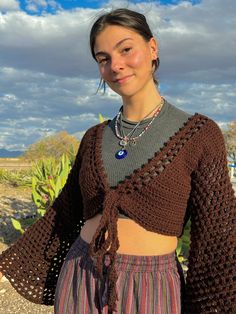 a woman wearing a brown crochet sweater and skirt with her hands in her pockets