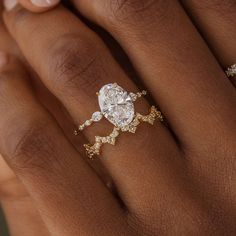 a woman's hand holding a diamond ring with two diamonds on it and the middle finger