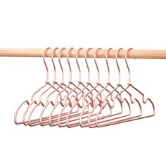 several clothes hangers are hanging on a wooden rod and one is pink, the other is white