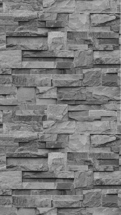 a black and white photo of a wall made out of stone blocks, with the top section