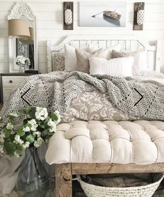 a bed with pillows and blankets on top of it next to a vase filled with flowers