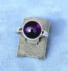 Amethyst ring hand made in my studio by me. The stone is 10 mm 4ct. The ring is size 4.5 , the ring can be sized up to a bigger size with limits. The ring weight is 4.7 grams. The band is 2mm thick. Any questions please message me. Thank you for looking. The photos are outdoor and indoor lighting Purple Amethyst Solitaire Ring, Purple Solitaire Round Ring, Round Solitaire Dome Ring Gift, Sterling Silver Cabochon Amethyst Ring, Purple Solitaire Amethyst Ring, Amethyst Ring With Large Stone, Adjustable Amethyst Birthstone Ring, Round Cabochon Amethyst Ring, Purple Solitaire Sapphire Ring