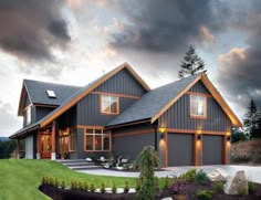 a large gray house sitting on top of a lush green field next to a forest