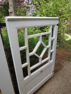 a white wooden gate in front of some trees