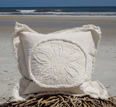 a white pillow sitting on top of a pile of seaweed next to the ocean