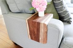 a vase with pink flowers sitting on top of a wooden table next to a couch