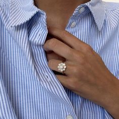 a woman wearing a blue and white striped shirt with a diamond ring on her finger