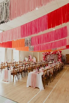 the tables are set up with pink and orange streamers hanging from the ceiling above them