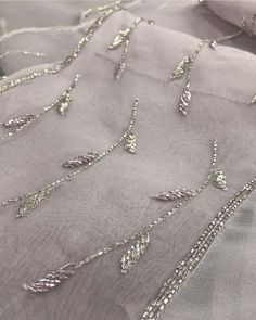 silver beaded fabric with beads and chains on the bottom, along with white linen