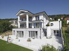 a large white house sitting on top of a lush green field next to a hillside