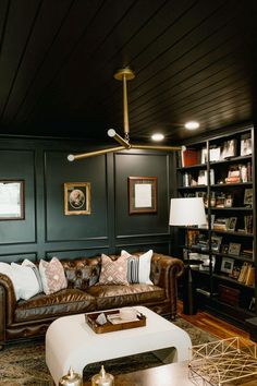 a living room with leather couches and bookshelves on the wall behind them