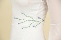 a woman's white dress with blue flowers embroidered on the chest and shoulderline