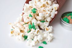 green and white sprinkles are scattered on the ground next to a tin of popcorn