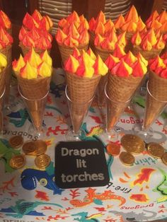 ice cream cones with orange and yellow flames in them on a table next to coins