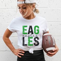 Show your school spirit with this Eagles shirt! Choose a different color from the drop-down menu. Color my vary slightly due to monitor settings. Made with 100% cotton. Fit: All shirts are unisex fit, true to size, loose fit. Recommend going up 1-2 sizes for an oversized look. Please check the size chart. If you have any questions, please contact us. Please check your address to make sure it is your current address. Care Instructions:  For the best and lasting results, wash in cold water inside out. No bleach. Dry on low heat or hang dry. Do not iron over design.  Returns: Because this item is made to order, all sales are final. No returns are accepted.  Please let us know if you have a problem with your order and we will try to correct the issue.  Shipping: Orders usually ship within 3 bu School Spirit Tops For Football Season Sports Events, Casual T-shirt For School Football Season, White Collegiate Tops For School, White Varsity Tops For School, Green Shirt With Team Name For Sports Events, School Spirit Tops With Screen Print For Football Season, Game Day Shirt With Team Spirit Screen Print, Football Season Screen Print Tops For College, Team Spirit Shirt With Screen Print For Game Day