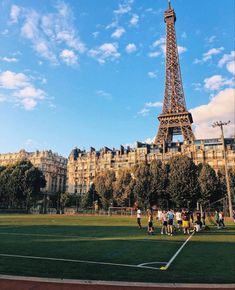 people playing soccer in front of the eiffel tower on a sunny day with blue skies