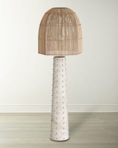 a white table lamp with a bamboo shade on it's top and floor in an empty room