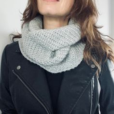 a woman wearing a gray knitted cowl with a black jacket and leather jacket