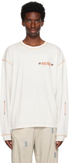 Cotton jersey T-shirt. · Rib knit crewneck and cuffs · Hand-stitched tatreez logo at chest · Hand-stitched tatreez detailing at sleeves · Logo patch at back collar · Textile patch at back hem · Contrast stitching in orange Supplier color: Off white White Embroidered T-shirt For Fall, White Cotton T-shirt With Ribbed Cuffs, White T-shirt With Ribbed Cuffs For Spring, Casual Contrast Stitching Sweatshirt For Streetwear, Casual Sweatshirt With Contrast Stitching For Streetwear, White T-shirt With Embroidered Text For Fall, White Crew Neck T-shirt For Spring, Long Sleeve Tops With Contrast Stitching For Streetwear, White Relaxed Fit Top With Embroidered Logo