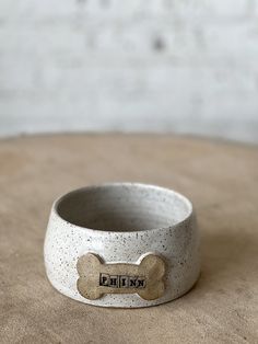 a ceramic dog bowl with a bone on the front and bottom, sitting on top of a table