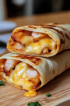 two burritos sitting on top of a wooden cutting board covered in cheese and sauce