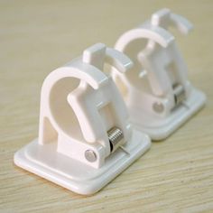 two white plastic clamps sitting on top of a wooden table next to each other