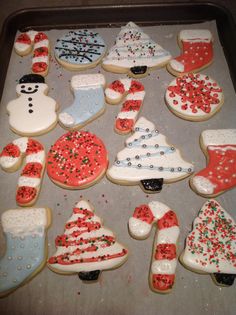 decorated cookies in the shape of christmas stockings and snowmen on a baking sheet with sprinkles