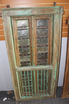 an old wooden door with metal bars on the bottom and sides, in front of a wood paneled wall