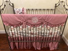 a baby crib with pink bedding and a monogrammed pillow