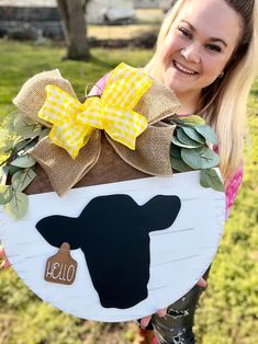 a woman holding up a sign with a cow on it