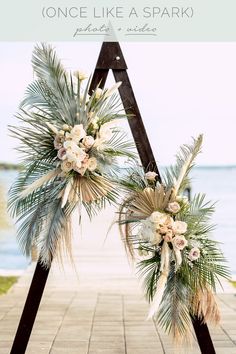 an arch decorated with flowers and greenery for a wedding ceremony at the ocean side