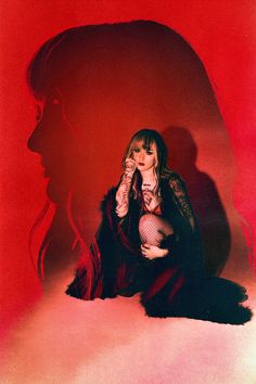 a woman sitting on the ground in front of a red background