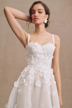 a woman wearing a white dress with flowers on it