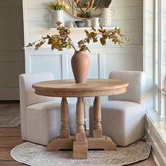 a table with two chairs and a vase on it in the middle of a room