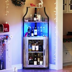 a lighted liquor cabinet in the corner of a room with christmas decorations on the wall