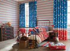 a bedroom decorated in red, white and blue with striped curtains on the windowsill