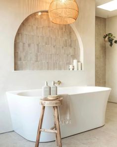 a white bath tub sitting next to a wooden stool