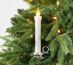 a white candle is hanging from a christmas tree with lights on it's sides