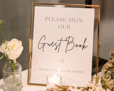 a guest book sign sitting on top of a table next to a vase with flowers