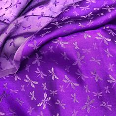 purple fabric with dragonflies on it and white flowers in the center, close up